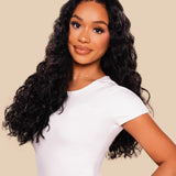 Woman with long, wavy hair wearing a white top against a beige background