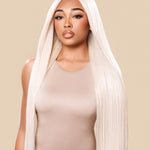 Woman wearing a beige bodysuit with a long blonde wig on a beige background