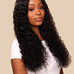 Woman with long, curly black hair wearing a white top on a beige background